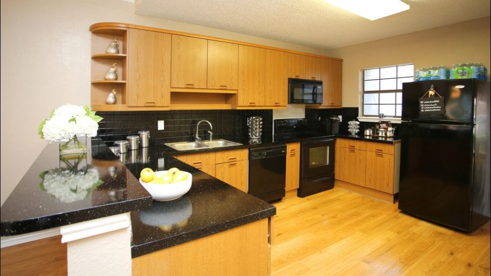 a kitchen with black appliances and wood cabinets at The Waterchase Gardens