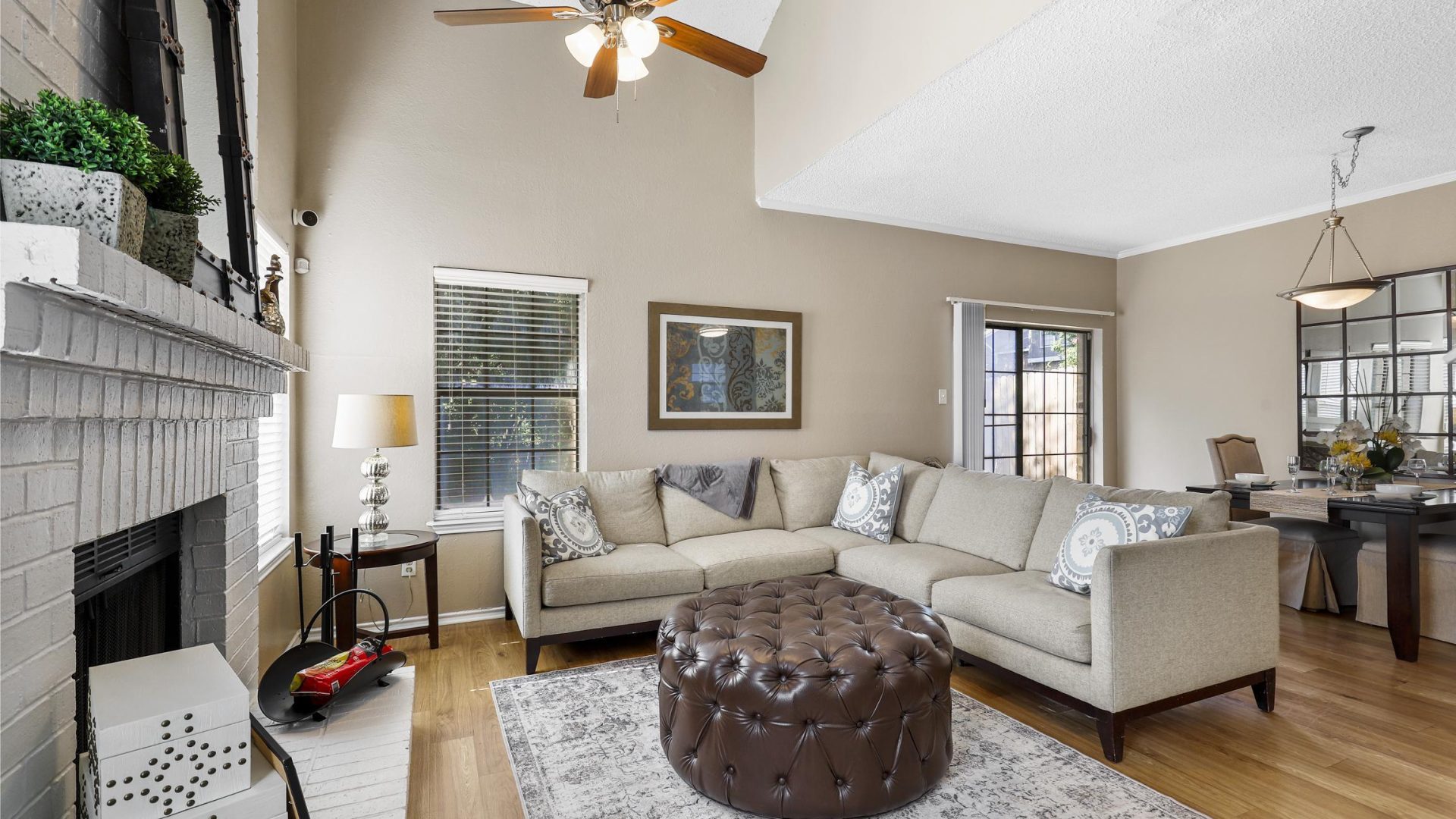 a living room with a fireplace and a ceiling fan at The Waterchase Gardens