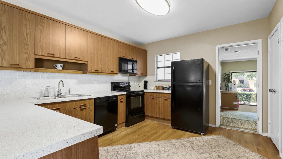 a kitchen with black appliances and wood cabinets at The Waterchase Gardens