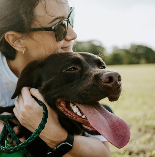 a woman in sunglasses hugging a dog at The Waterchase Gardens