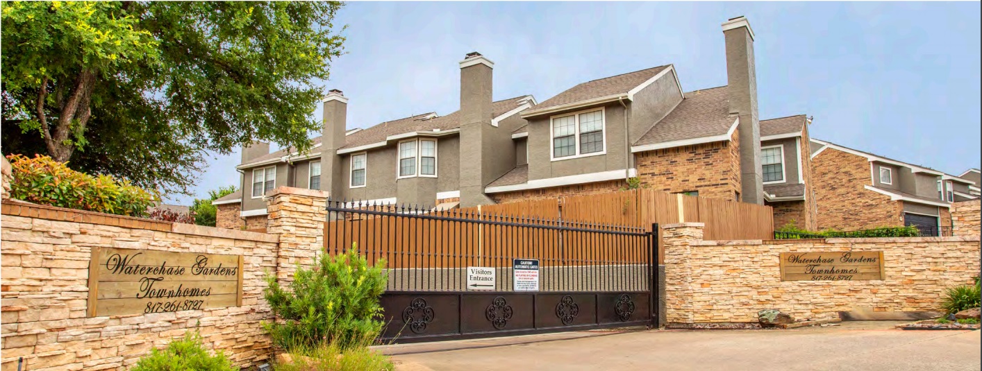 the gate to a residential neighborhood with a fence at The Waterchase Gardens